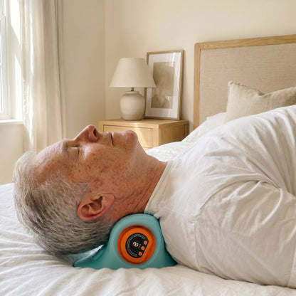Uomo che usa il massaggiatore cervicale Exos a letto